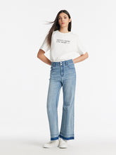 A lady wears a top and jeans.